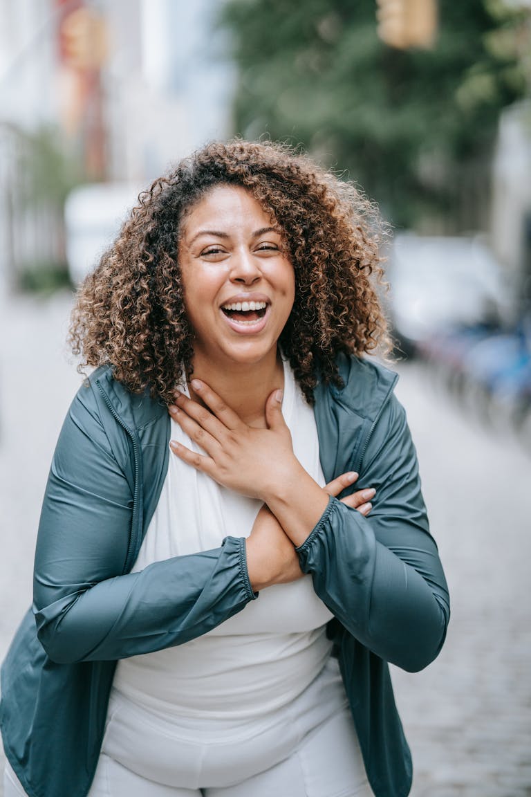 Ashamed of Taking Ozempic? The Truth From a DietitianHappy woman with curly hair laughing outdoors on a city street, expressing joy and freedom.